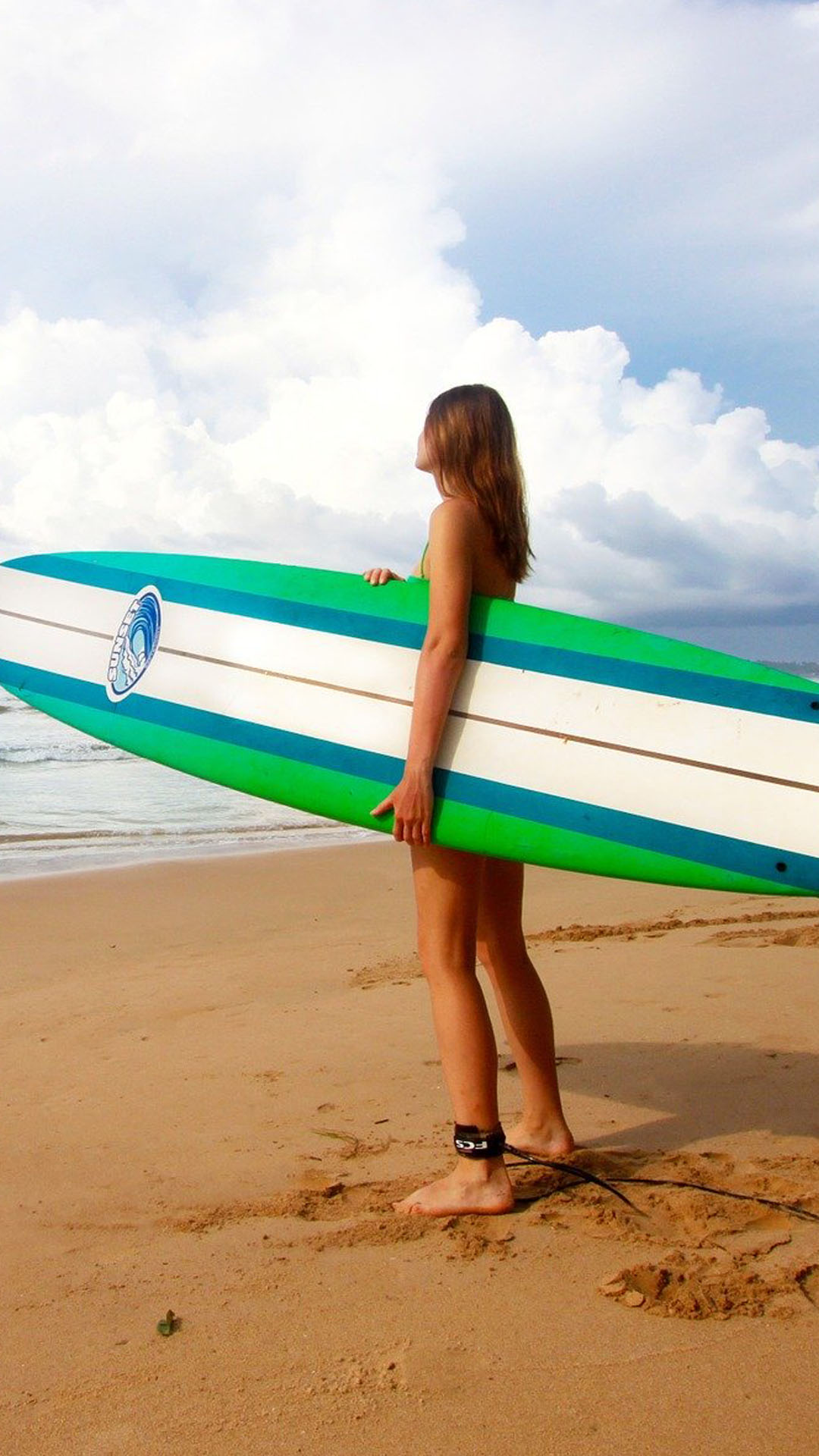 Jeune femme avec sa planche de surf au bord de la mer